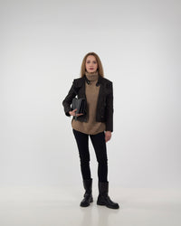 Full-length styling of the Diva biker jacket in black technical suede, layered over a tan knit sweater with black trousers and boots