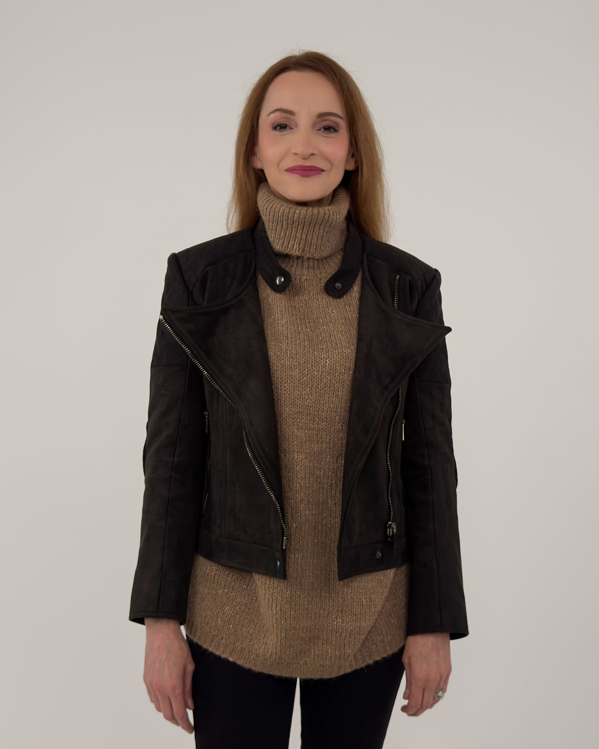 The Diva jacket in black technical suede, shown open over a high-neck tan sweater to highlight the soft, breathable Italian fabric